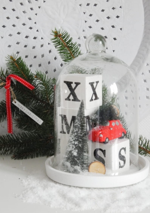 Dekoracja świąteczna pod kloszem z zimową sceną i czerwonym samochodzikiem