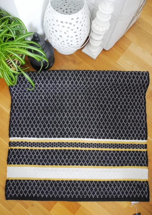 Czarny dywanik ywan bawełniany 70x140cm na podłodze w sypialni