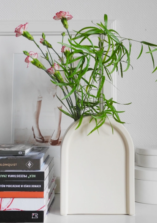 Kremowy ceramiczny wazon w kształcie łuku – hołd dla elegancji art déco - z bukietem goździków