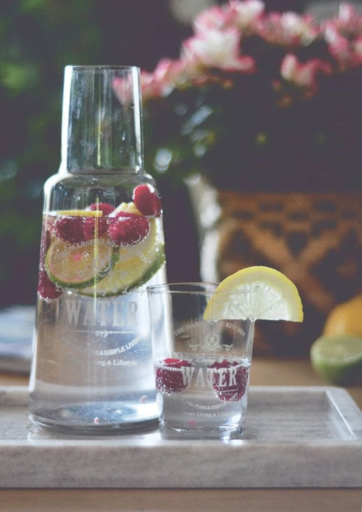 Karafka i szklanki do wody na stole z dodatkiem świeżych owoców