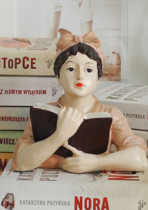 Ozdobna figurka czytająca kobieta w różowej bluzce i opasce