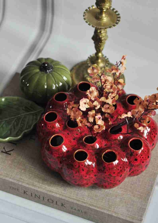 Bordowy wazon ceramiczny z otworami w stylu vintage na lnianej książce