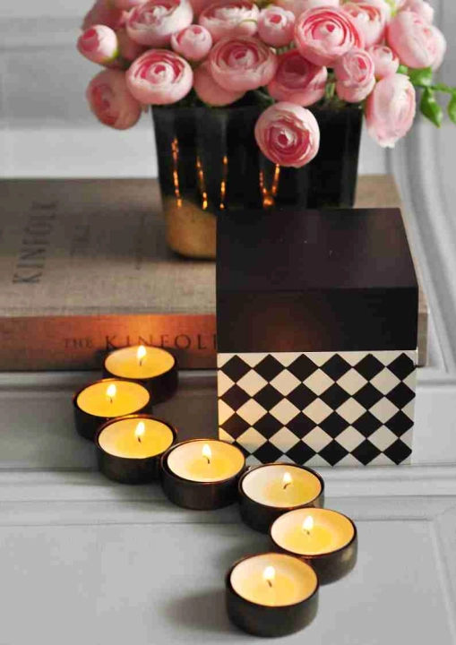 Świecznik na tealight gąsienicowy, metalowy dekor w stylu minimalistycznym obok różowych kwiatów.