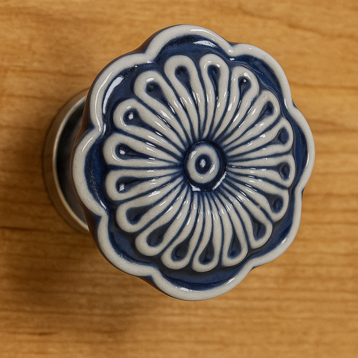 Zbliżenie na niebieską ceramiczną gałkę meblową z białym wzorem kwiatowym na tle drewnianej komody