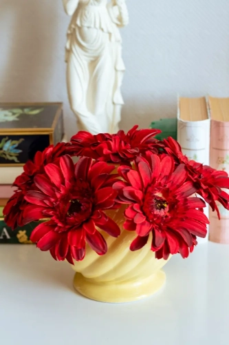 Tulipaniera ceramiczna w kolorze żółtym wypełniona czerwonymi kwiatami