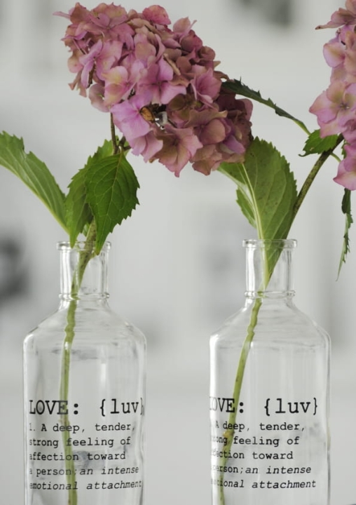 Butelka z napisem LOVE jako szklany wazon na pojedyncze kwiaty – aranżacja w stylu minimalistycznym